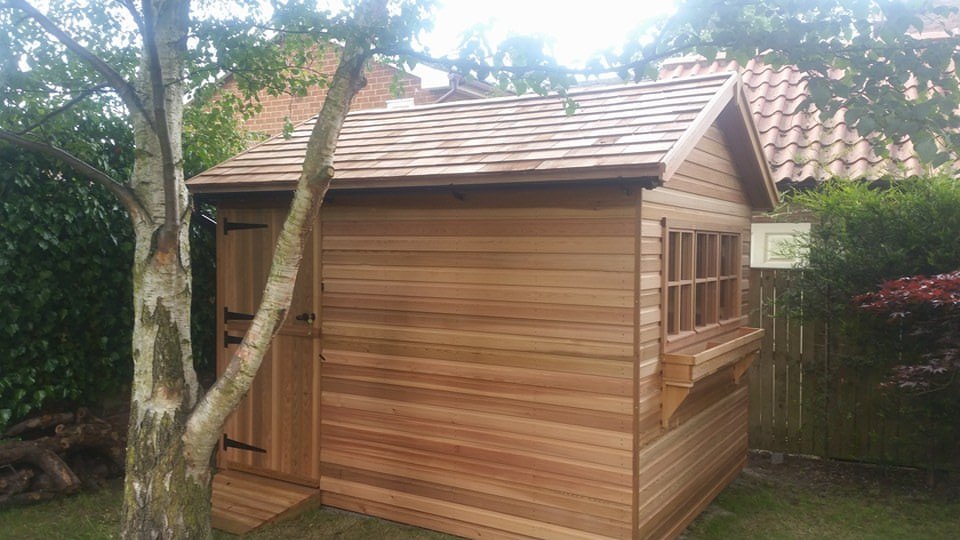 Western red cedar shed Horizontally fixed western red cedar cladding and roof shingles with hardwood window frames.